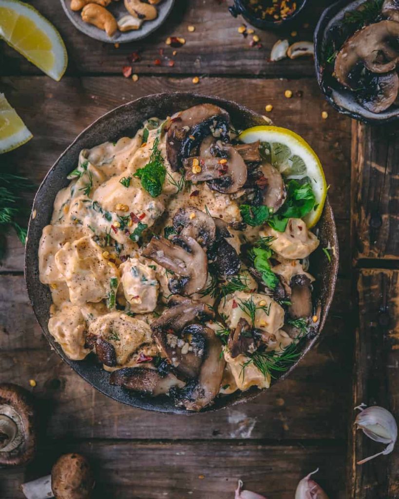A photo of a bowl of cheesy tortellini with garlicky mushrooms on top