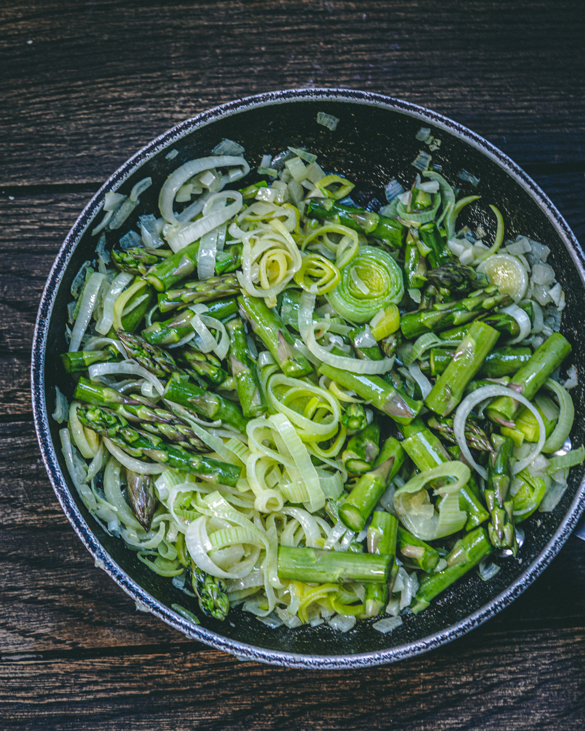 Asparagus sauteing in a pan with shallots 